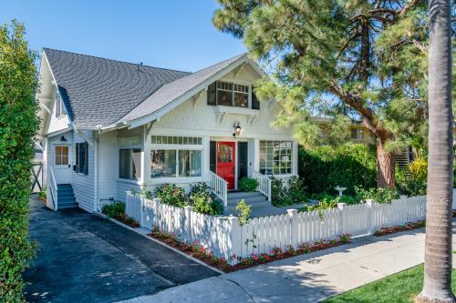a white house with a red door and a white fence at The Sea Captains House & Loft by Paradise Retreats in Santa Barbara