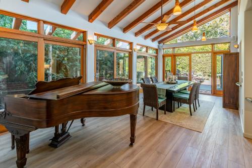 a conservatory with a piano and a table with chairs at Tropical Retreat by Paradise Retreats in Santa Barbara