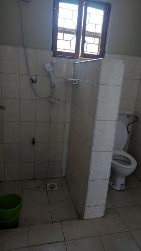 a bathroom with a shower with a toilet and a window at J and A Villas Homestay in Mbale