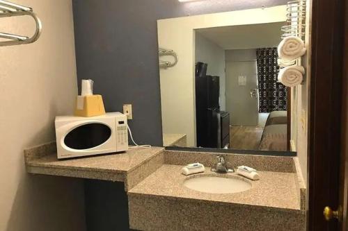 a bathroom with a sink and a microwave on a counter at Best Value Inn Garland, TX in Garland