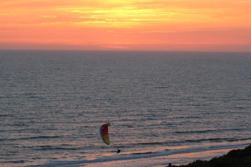 a person flying a kite over the ocean at sunset at Hotel Doñana Blues in Matalascañas