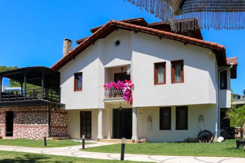 a white house with pink flowers on the balcony at Mints Hotel Ağva in Agva
