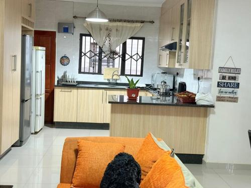eine Küche mit einer orangefarbenen Couch in einem Zimmer in der Unterkunft Twinhome Inn in Gaborone