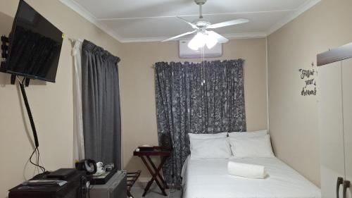 a bedroom with a bed and a ceiling fan at Serenity in Windhoek