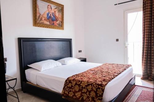 ein Schlafzimmer mit einem Bett und einem Bild an der Wand in der Unterkunft Apart Hotel Larabi in Marrakesch