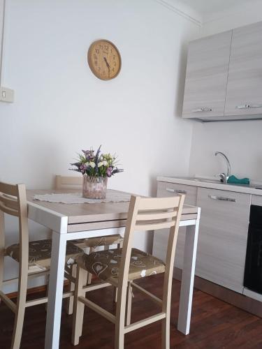 a kitchen table with two chairs and a clock on the wall at Casa Eva Roreto in Roure Turin