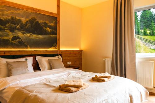 a bedroom with a bed with two towels on it at Pensiunea Poienita Ursului in Fundata