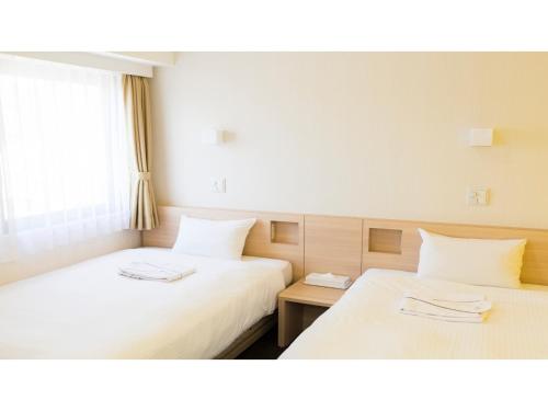 two beds in a hotel room with white sheets at Smile Hotel Utsunomiya Higashiguchi - Vacation STAY 00213v in Utsunomiya