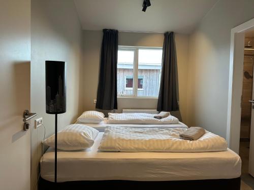 three beds in a room with a window at Álfheimar Hotel in Borgarfjordur Eystri