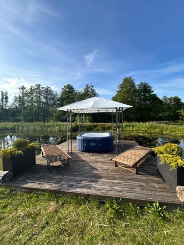 a wooden dock with a tent and benches on a lake at Monasteria in Stare Monasterzysko