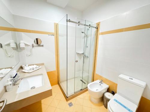a bathroom with a shower and a toilet and a sink at Bel Ami Suita Hotel in Vlorë
