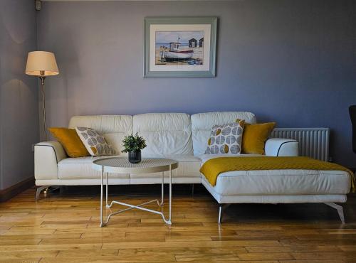 a living room with a white couch and a table at Beachside - Stunning sea view townhouse across the road from the beach in Kilkeel