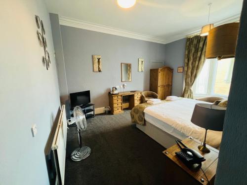 a bedroom with a bed and a desk and a window at The George Hotel in Montrose