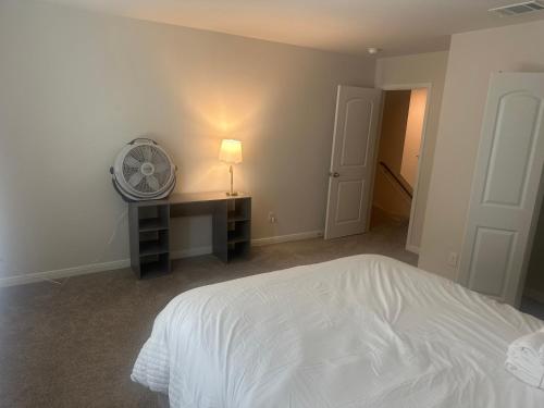 a bedroom with a white bed and a desk with a fan at Cozy, Comfy and Relaxing! 