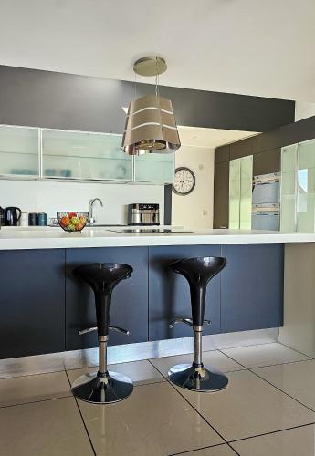 a kitchen with black bar stools and a sink at Beachside - Stunning sea view townhouse across the road from the beach in Kilkeel