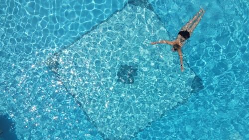 a man swimming in a pool of water at Riviera Perdika Hotel in Perdika