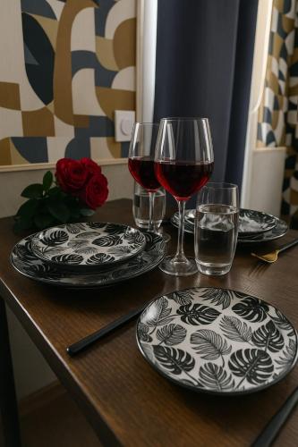 - une table avec deux verres de vin rouge et des assiettes dans l'établissement Studio & Balnéo privatif, à Évreux