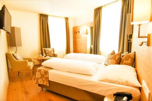 a hotel room with two beds and a chair at Das Alte Rathaus in Egna