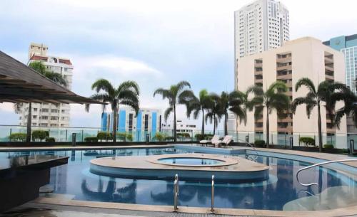 a large swimming pool with palm trees and buildings at bayviewmansion malate in Manila