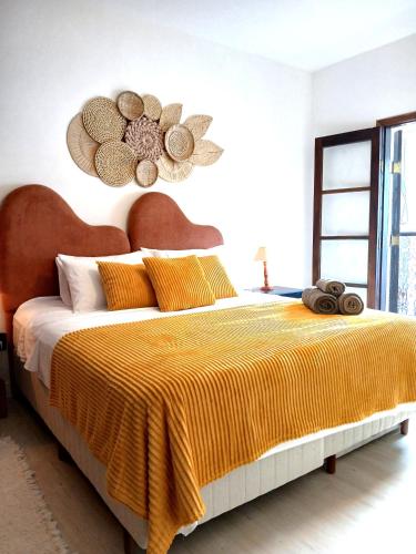 a bedroom with a large bed with a yellow blanket at Suíte Casal com Hidro no Centro - Infinito Particular in Guararema