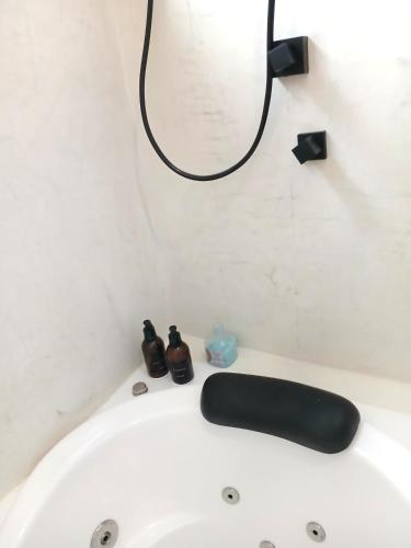 a white bath tub with a black light on the wall at Suíte Casal com Hidro no Centro - Infinito Particular in Guararema
