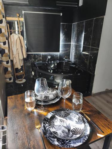 - une table avec deux assiettes et des verres à vin dans l'établissement Studio & Balnéo privatif, à Évreux