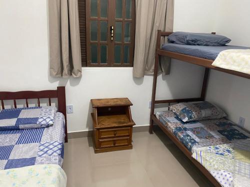 a bedroom with two bunk beds and a table at Casa unamar, cabo frio - RJ in Cabo Frio