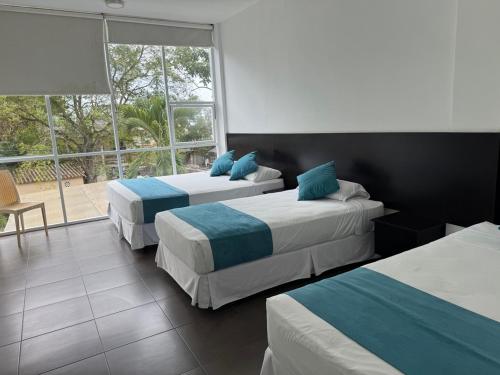 a hotel room with two beds and a window at Ocean Blue Hotel in Olón