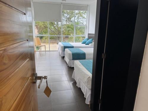 a room with three beds and a window at Ocean Blue Hotel in Olón