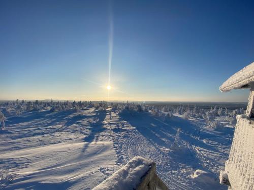 a snow covered field with the sun in the sky at Villa Kelo - Casual Luxury in Lapland, Salla in Salla