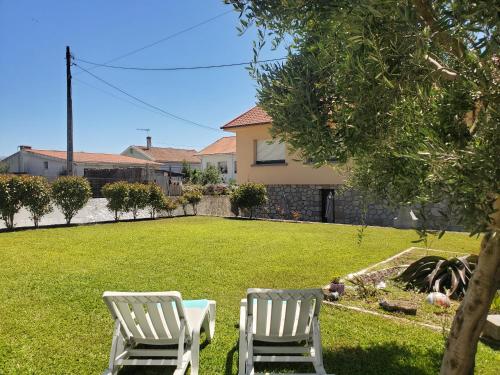 two white chairs sitting in the grass in a yard at Villa Ribeiro in Vila Praia de Âncora