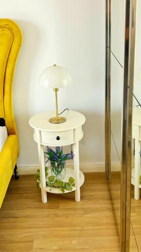 a white table with a lamp on it next to a bed at Adina Cosmopolis in Ştefăneştii de Jos