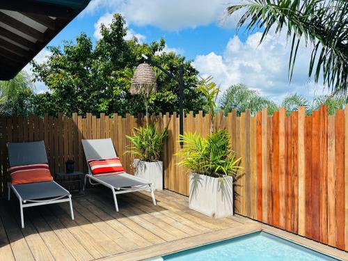 two chairs sitting on a deck next to a fence at ZANNANNA LODGE in Le Diamant