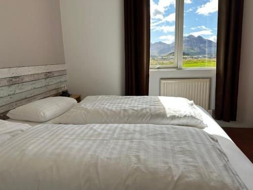 a bedroom with a white bed and a window at Álfheimar Hotel in Borgarfjordur Eystri