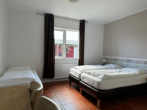 two beds in a room with a window at Álfheimar Hotel in Borgarfjordur Eystri