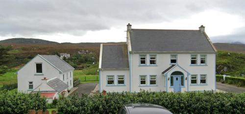 a large white house with a car parked in front of it at An Teach Beag Glencolmcille, little home from home in Glencolumbkille