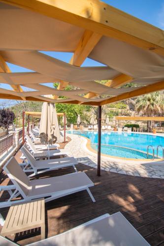 a row of lounge chairs under an umbrella next to a pool at Riviera Perdika Hotel in Perdika