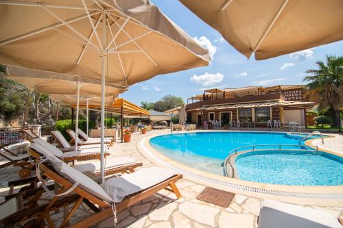 a resort pool with chairs and umbrellas at Riviera Perdika Hotel in Perdika