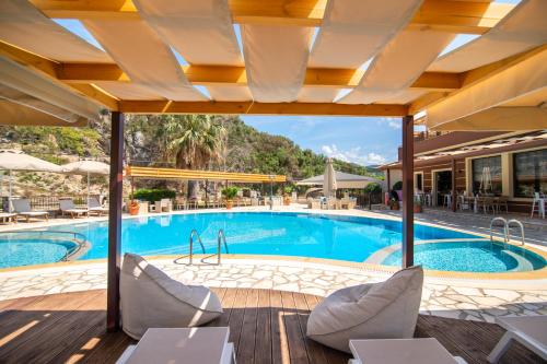a pool at a hotel with tables and chairs at Riviera Perdika Hotel in Perdika