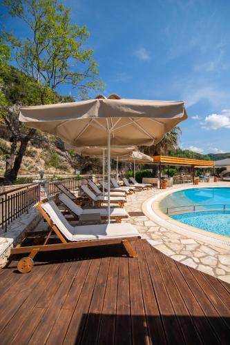 a deck with chairs and an umbrella next to a pool at Riviera Perdika Hotel in Perdika