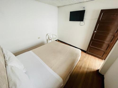 a small bedroom with a bed and a television at Hotel Colonial El Gran Fénix in Tunja