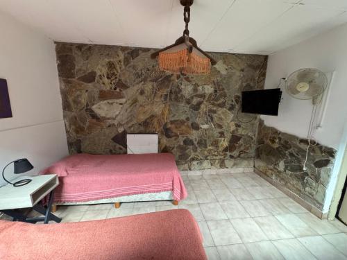a bedroom with a pink bed and a stone wall at Jujuy Hostel in San Salvador de Jujuy