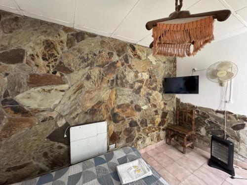 a room with a stone wall with a tv and a couch at Jujuy Hostel in San Salvador de Jujuy