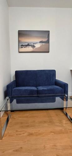 a blue couch in a room with a picture on the wall at New Royal Inn in New Westminster