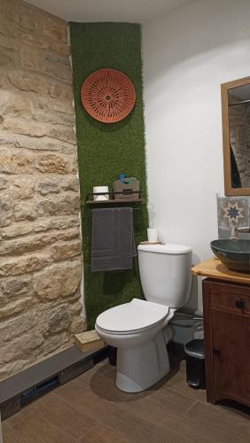 a bathroom with a toilet and a stone wall at La Tourelle - Gite et chambre d'hôte in Saint-Antonin