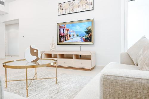 a living room with a tv on a wall at Spacious 2BR in Ansam Yas Island Views Sleeps 7 in Abu Dhabi