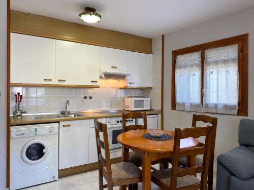 a kitchen with a table and chairs and a kitchen with a sink at Apartamentos Lausan in Gavín