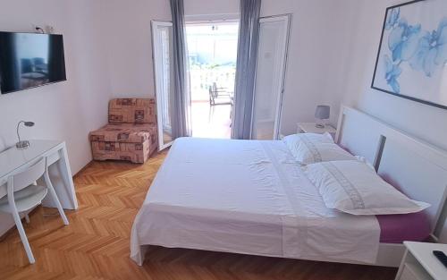 a bedroom with a white bed and a desk and a window at Apartments Mate Slavic in Sućuraj