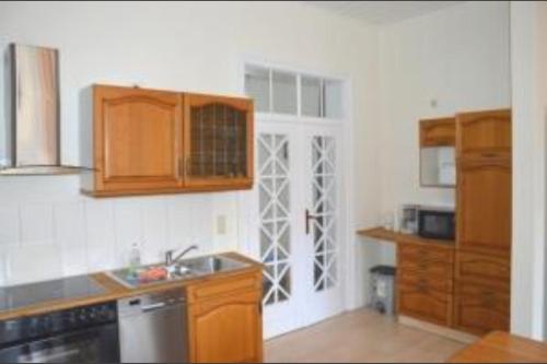 a kitchen with wooden cabinets and a sink and a door at Ferienwohnung Fritz in Zinnowitz