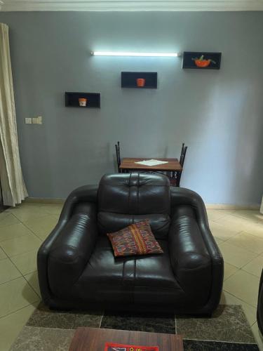 a black leather couch in a living room with a table at Résidence H - Ekoumdoum in Yaoundé